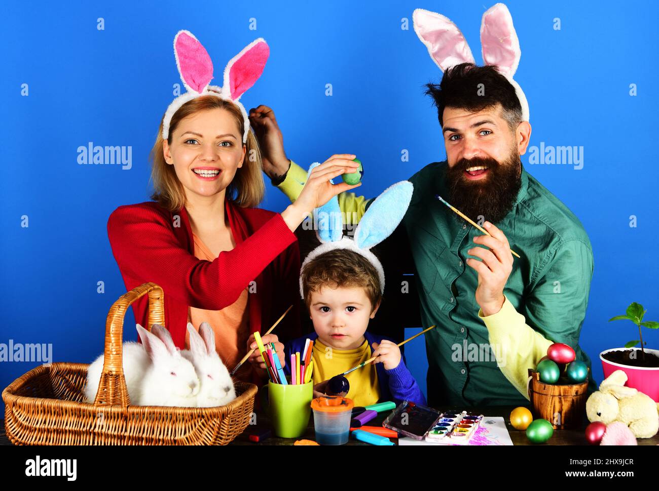 Kaninchen Familie malen Eier. Mutter, Vater und Sohn in Hasenohren bereiten sich auf Ostern vor. Stockfoto