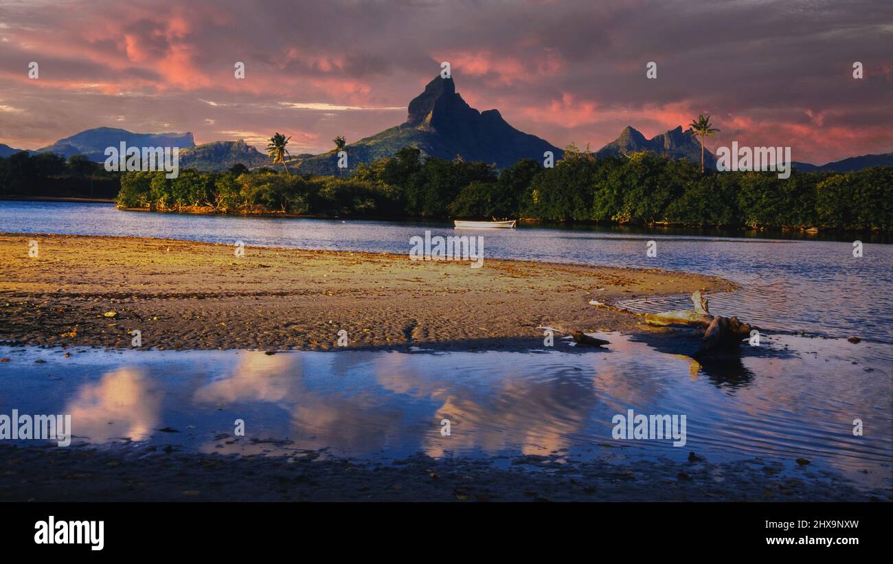 Tamarin Bay, Mauritius, bei Sonnenuntergang, mit Wolken Reflexion auf dem Wasser und Gebirge und Wald im Hintergrund Stockfoto