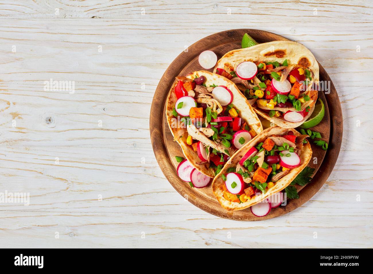 Pitacos, mexikanische Tacos mit Pita-Brot, würziges Hühnerfleisch, rote Nierenbohnen, Mais, Rettich, roter Pfeffer, Süßkartoffeln und Limette auf Holz rösten Stockfoto