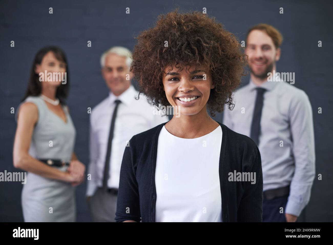 Das Team, das immer seine Ziele übertrifft. Aufnahme einer jungen professionellen Frau, die vor einer Gruppe von Mitarbeitern steht. Stockfoto