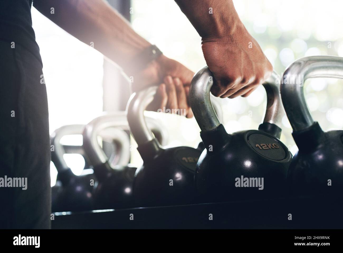 Haltet an den Dingen fest, die euch stark machen. Ein kurzer Schuss eines nicht erkennbaren Sportlers, der in einem Fitnessstudio die Kettelglocken hebt. Stockfoto