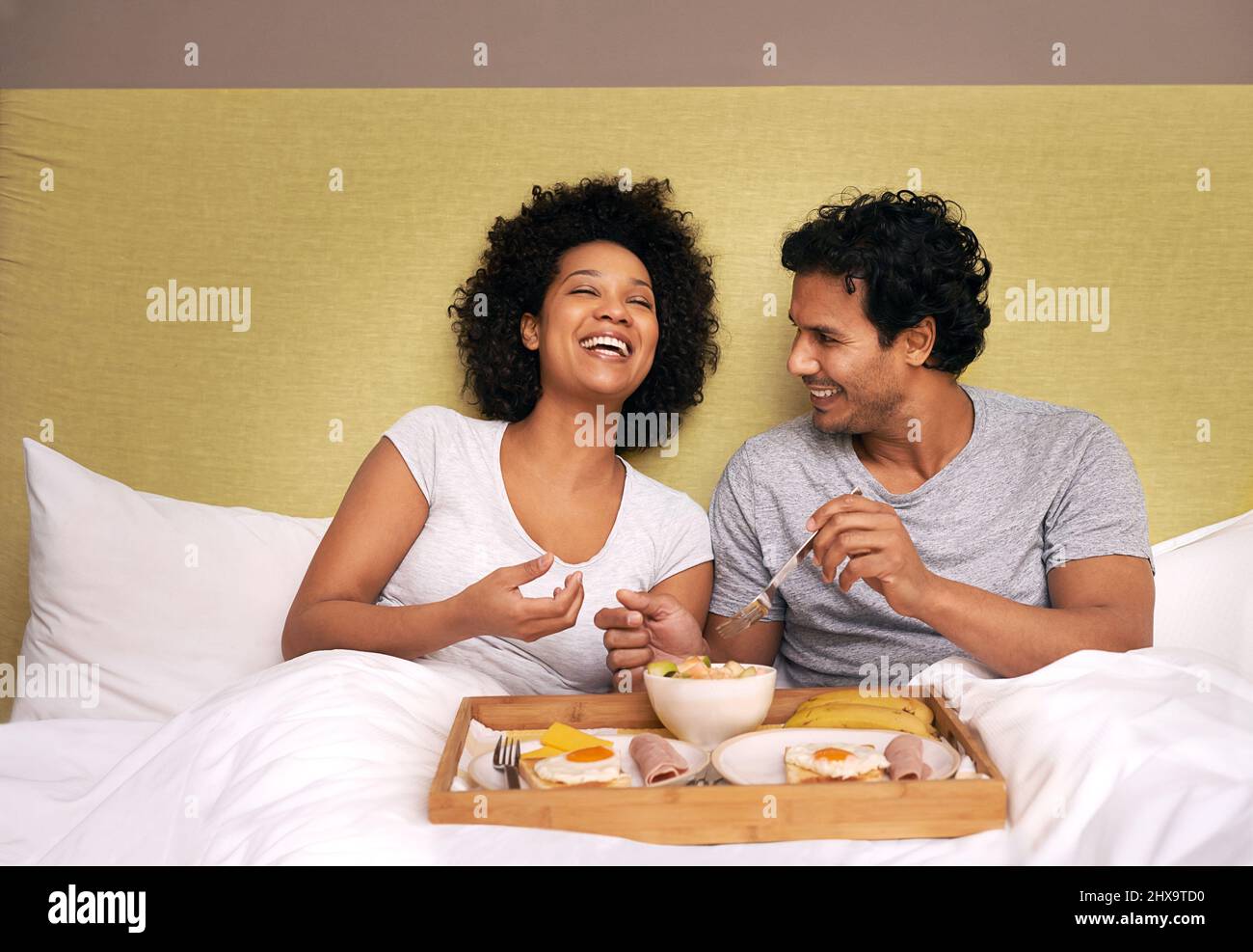 Frühstück im Bett. Ein süßes Paar, das sich das Frühstück im Bett teilt. Stockfoto