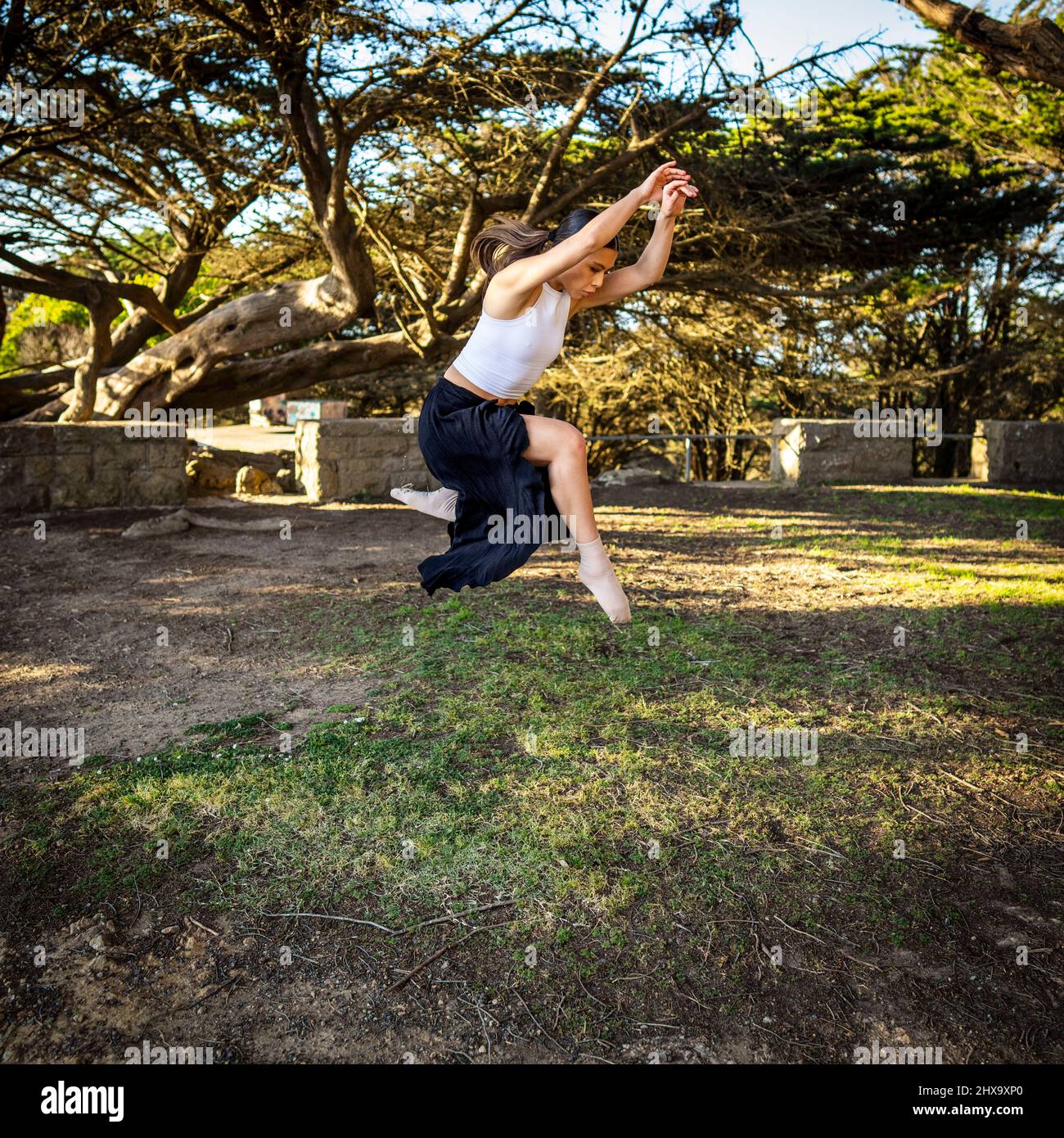 Teenager-Tänzerin beim Springen im baumgesäumten Park Stockfoto