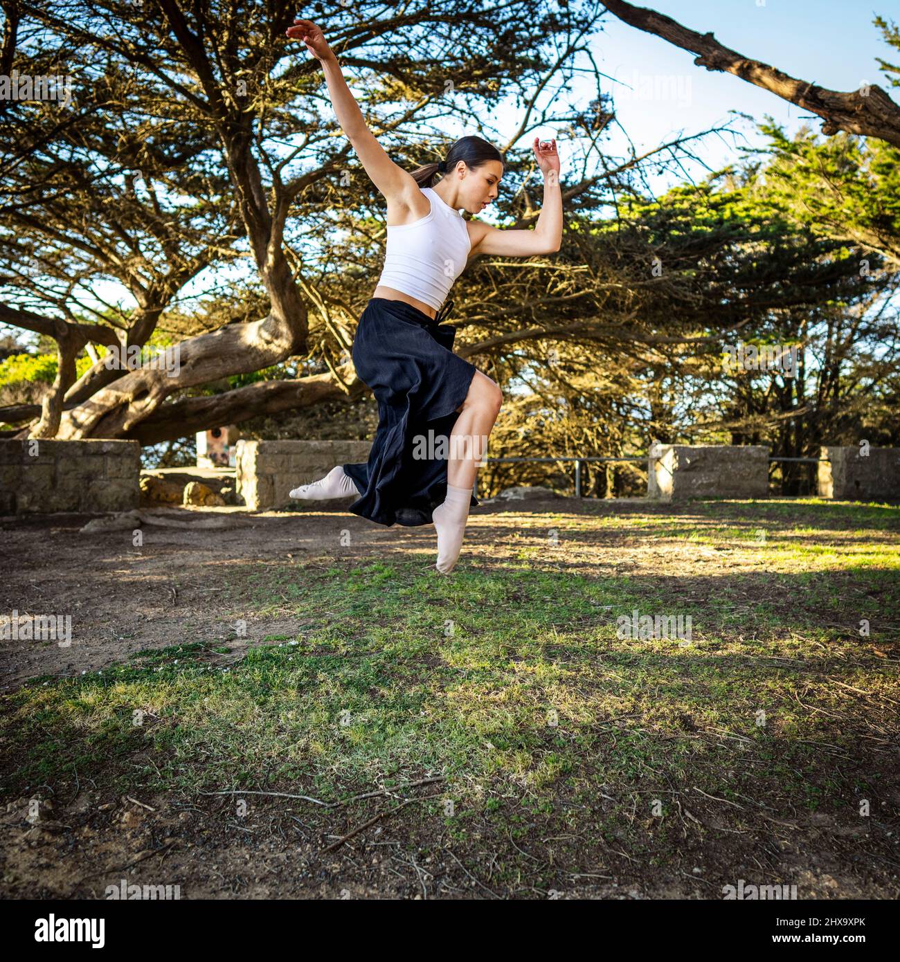 Teenager-Tänzerin beim Springen im baumgesäumten Park Stockfoto