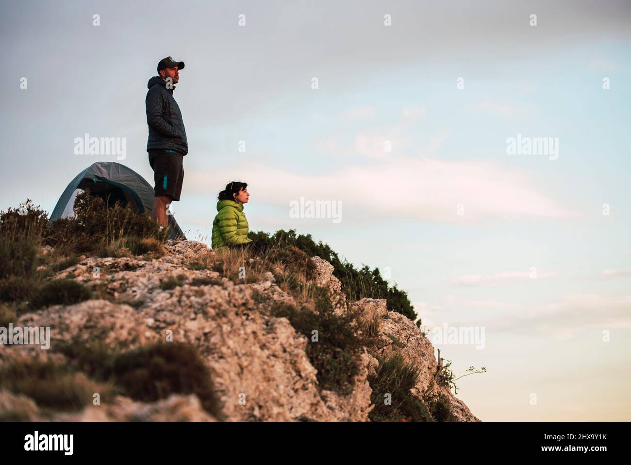 Frau und Mann sitzen auf der Klippe mit Blick auf die Landschaft. Stockfoto