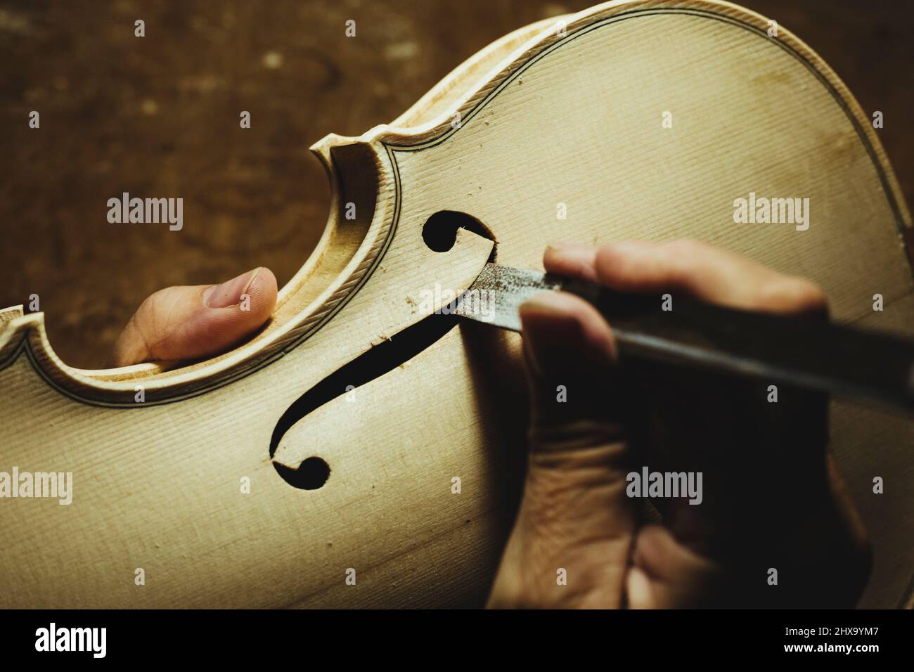 Unbekannter Geigenbauer, der eine Geige kreiert und Werkzeuge verwendet Stockfoto