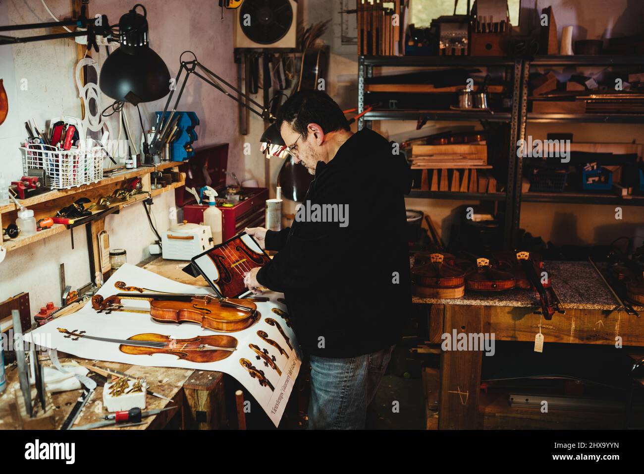 Geigenbauer prüft Pläne für die lackierte Geige auf Papier und weiter Stockfoto