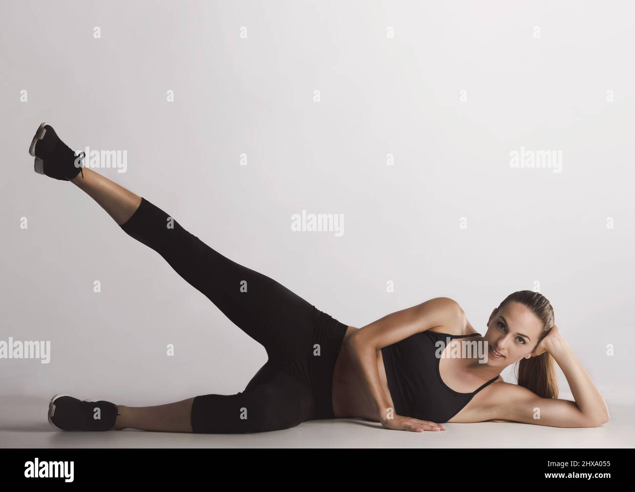 Fitness-Frau – Beinheben in seitlicher Liegelage Stockfoto