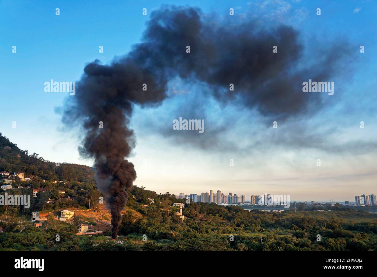 Eine riesige schwarze Rauchsäule in verwahrloster Erde Stockfoto