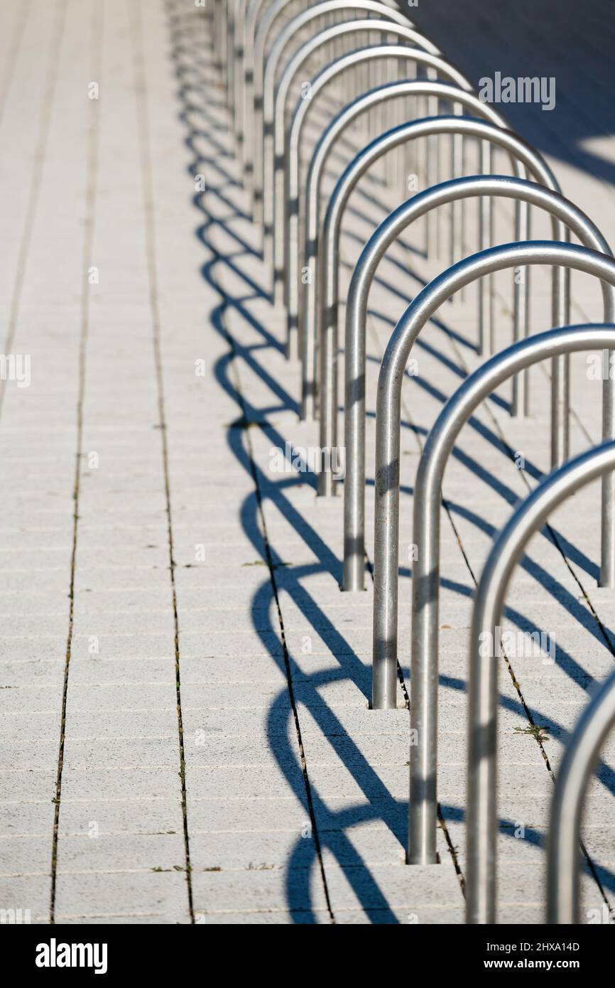 Vertikales Bild perspektivische Ansicht von mehreren Edelstahl gesicherten leeren Fahrradständer mit seinen Schatten leeren Racks entworfen, um Fahrräder im städtischen Stadtgebiet zu parken Stockfoto