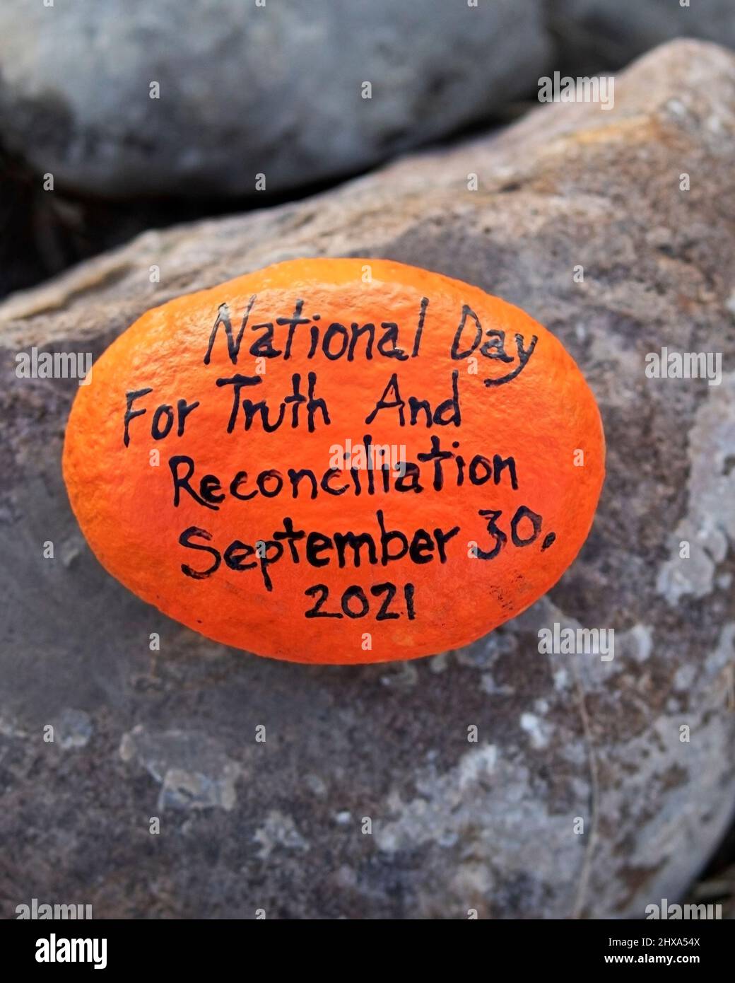 Orangefarbener Stein mit den Worten Nationalfeiertag für Wahrheit und Versöhnung der 30. September 2021 wurde als Gedenkstätte im Nose Hill Park in Calgary, Kanada, hinterlassen Stockfoto