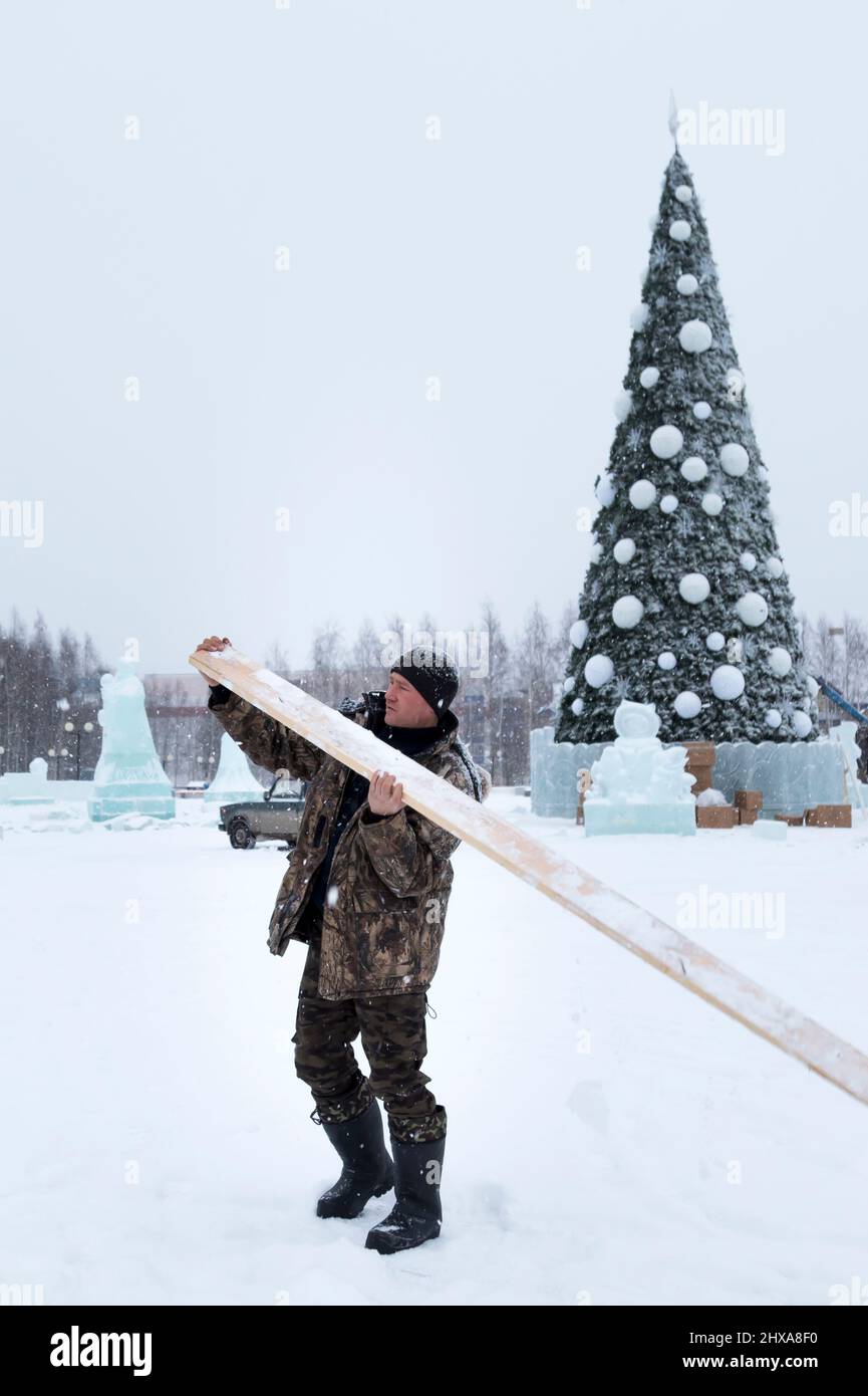 Baumeister mit einem Brett in den Händen auf dem Hintergrund des Weihnachtsbaums Stockfoto