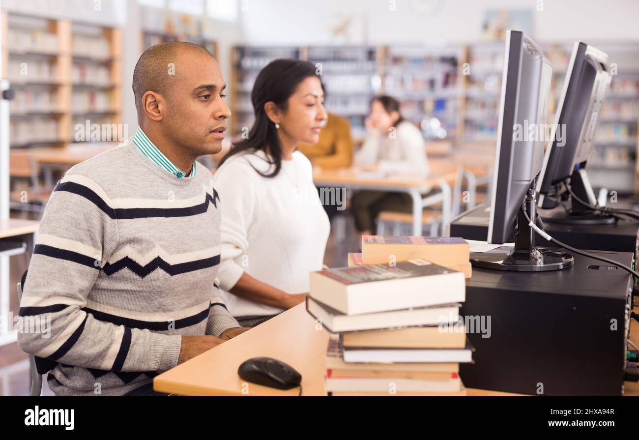 lateinamerikanischer Mann, der in der Computerklasse in der öffentlichen Bibliothek studiert Stockfoto