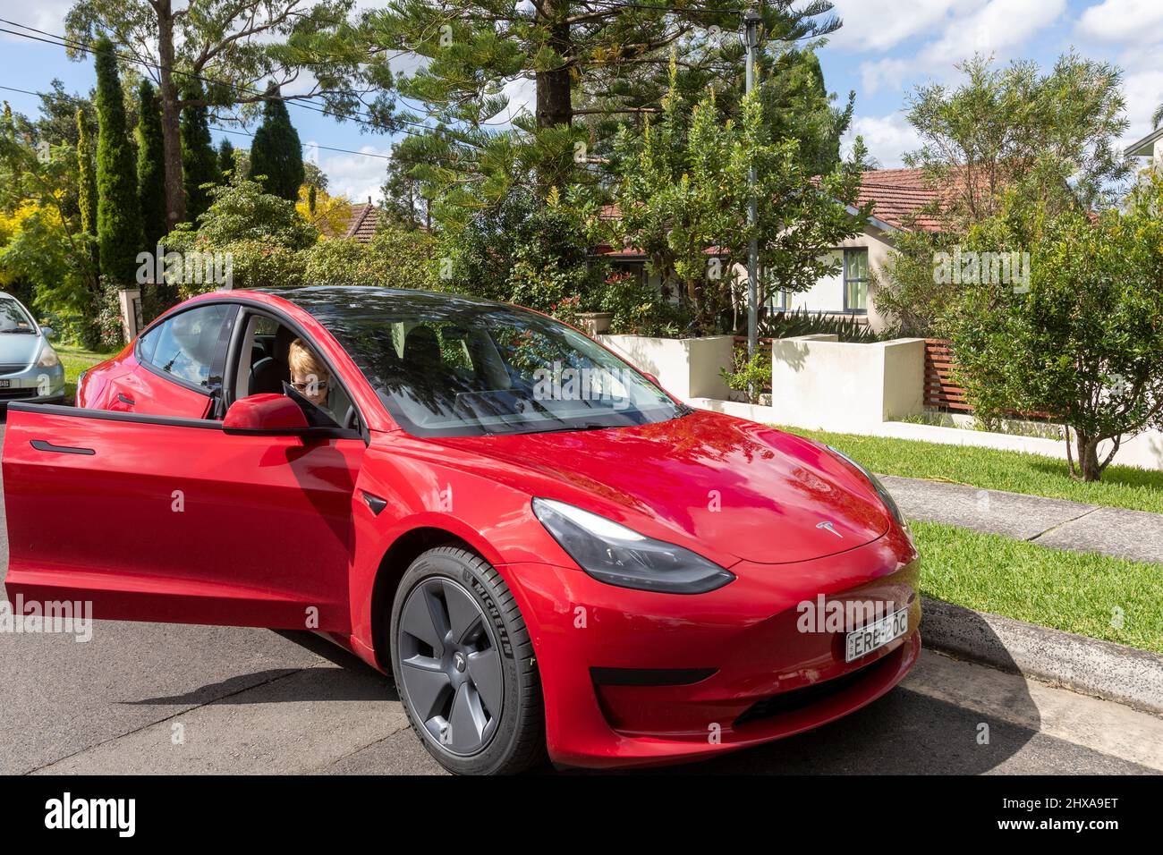 2022 rotes Tesla Modell 3 mit Dame mittleren Alters, Model freigegeben, aus dem Auto treten auf Fahrerseite, Sydney, Australien Stockfoto