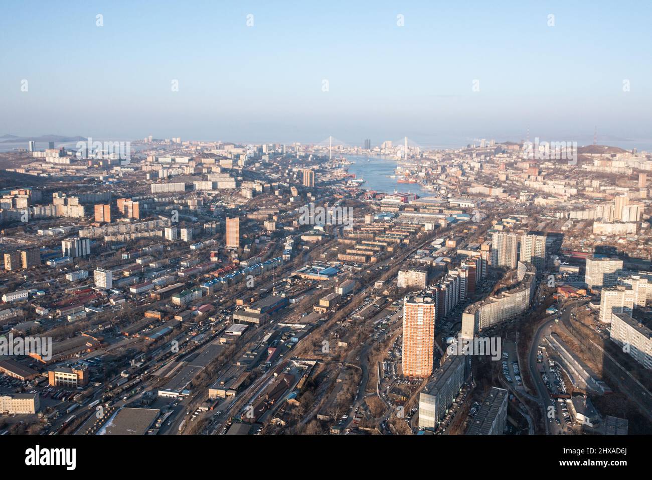 Wladiwostok, Russland - 5. Februar 2022:Blick von oben auf die Häuser und Straßen der Stadt. Am Horizont können Sie das Meer und die Brücken sehen. Stockfoto