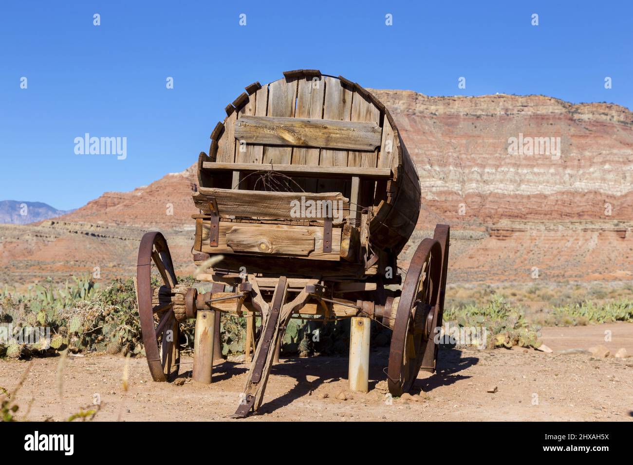 Isolierte alte Vintage Holz Wild West Stage Coach Wagon Rad Replik mit Western Red Rock Canyon Cliffs Utah Landschaft im Hintergrund Stockfoto