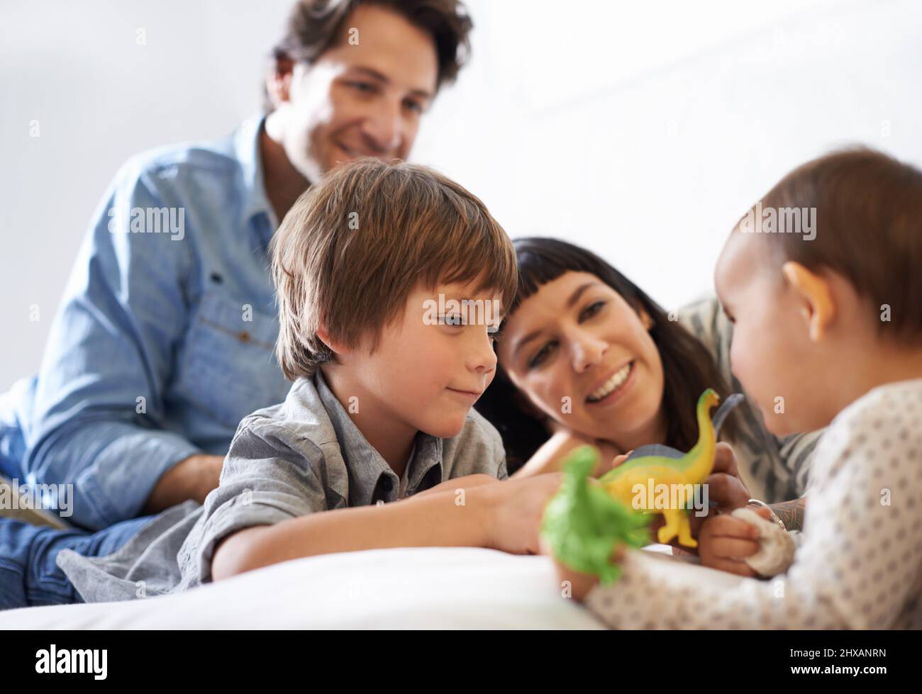 Big Brother Bonding. Aufnahme eines glücklichen Bruders und einer glücklichen Schwester, die mit ihren Spielzeugen spielen, während ihre Eltern auf sie schauen. Stockfoto