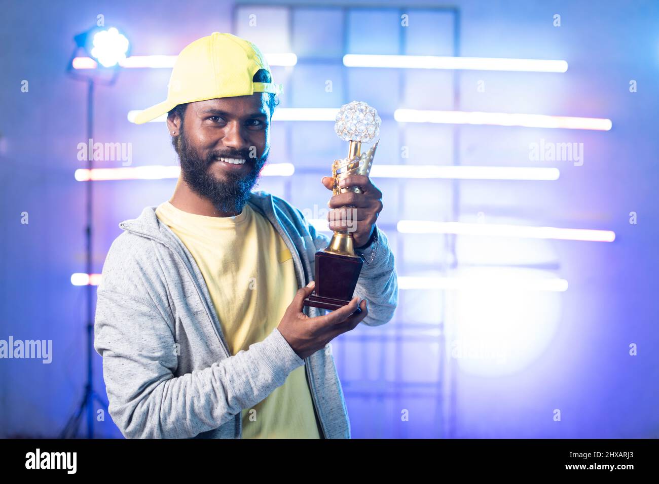 Happy Smiley Junge Tänzerin mit Siegertrophäe in den Händen Blick auf die Kamera auf der Bühne mit Kopierraum - Konzept der Leistung, stolz und inspirierend Stockfoto