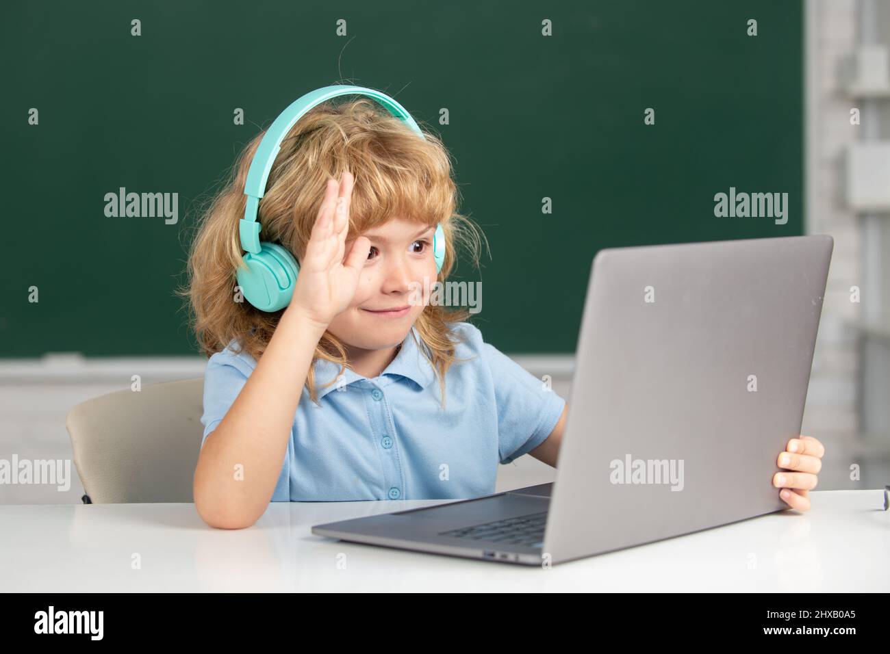 Cleverer Schuljunge, niedlicher Schüler trägt Kopfhörer, die auf dem Laptop schreiben, hören Sie Audiounterricht am Computer. Videocall, E-Studie mit Tutor entfernt. Stockfoto