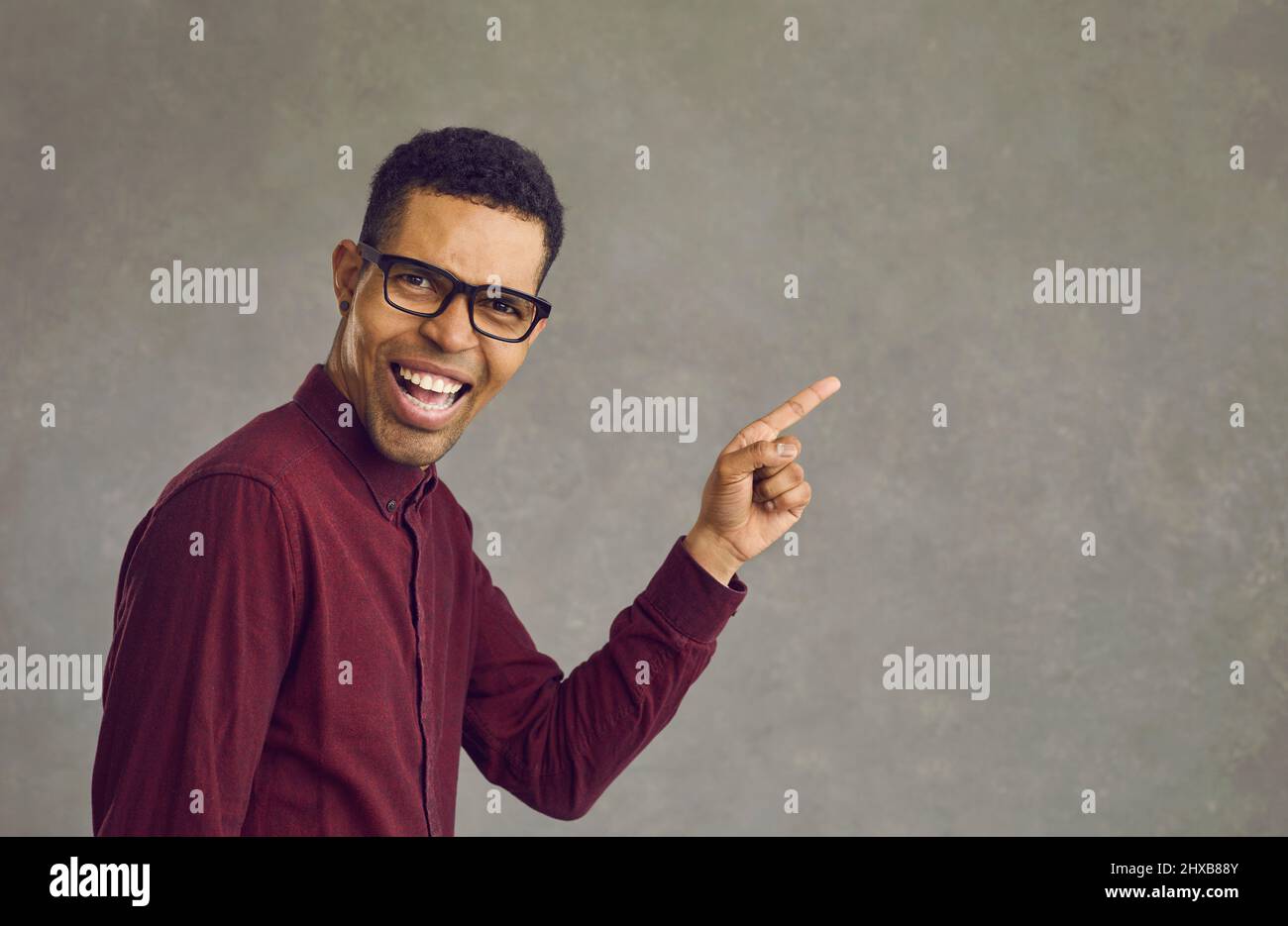 Hübscher junger afroamerikanischer Mann, der lachend mit dem Finger auf den Kopierraum zeigt Stockfoto