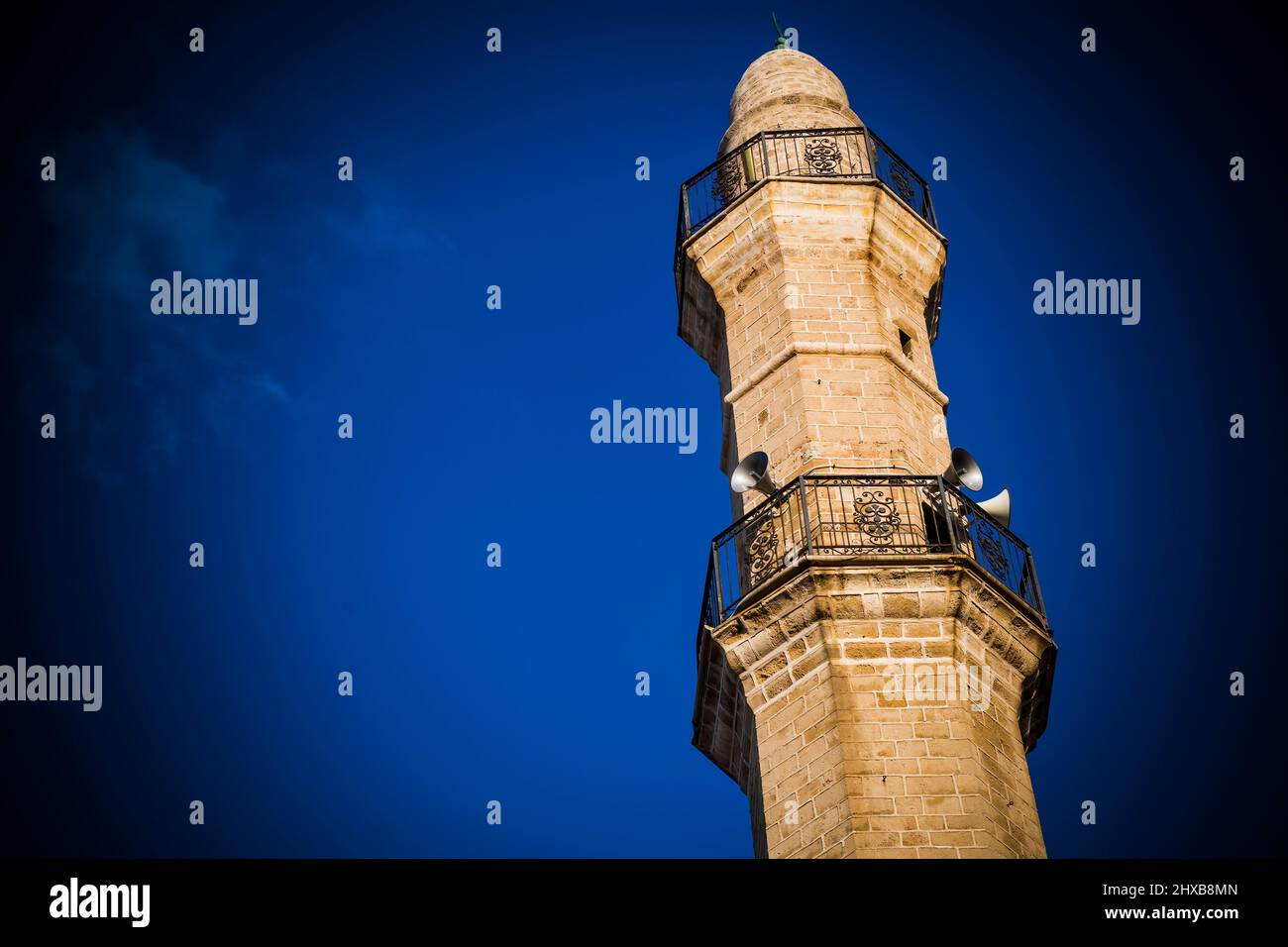 Moschee-Turm in starkem Sonnenlicht gegen tiefblauen Himmel Stockfoto