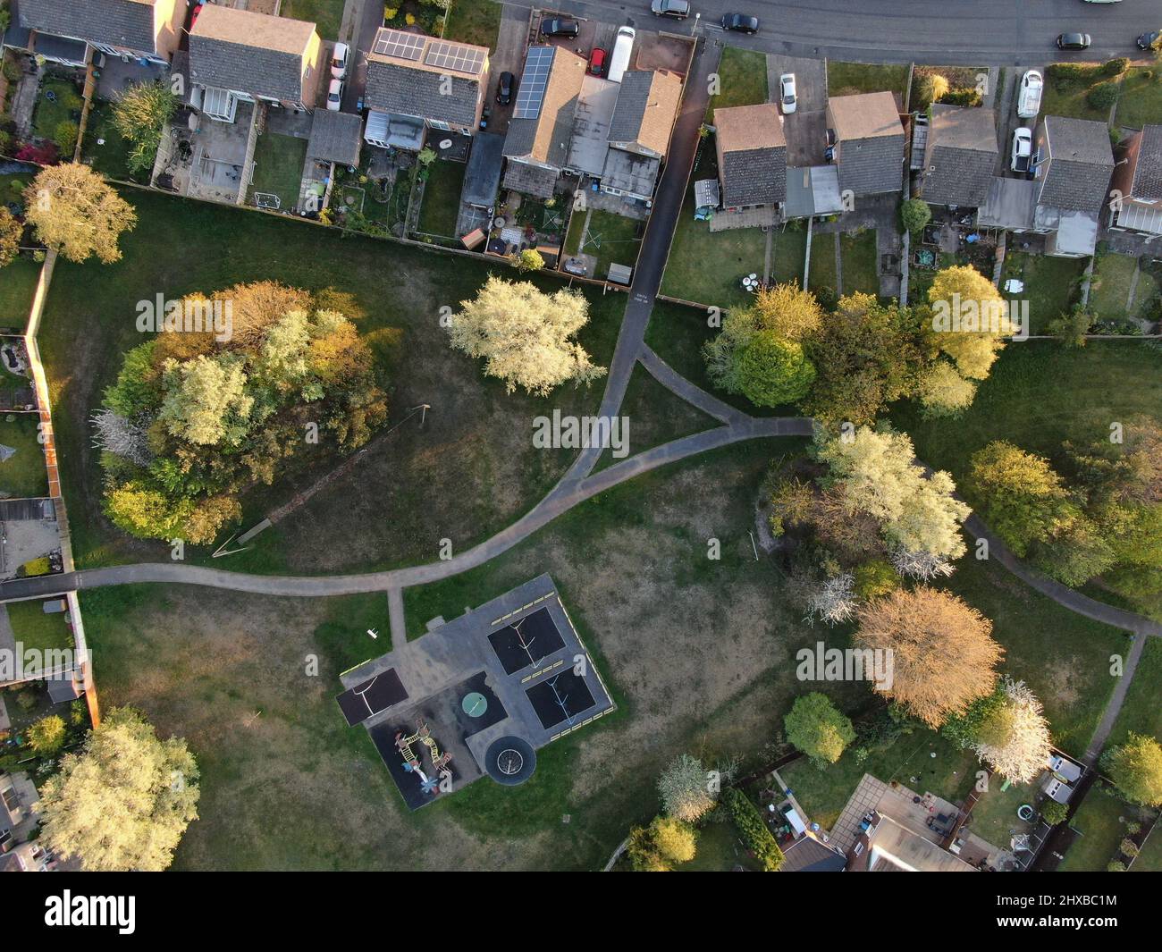 Luftaufnahme von direkt über einem kleinen, von Bäumen umgebenen und von Häusern umgebenen Spielplatz Stockfoto