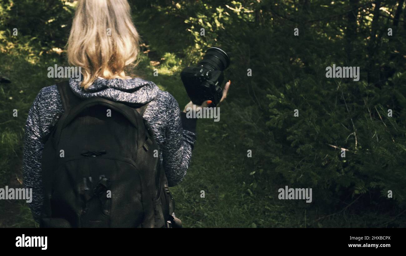 Traveler fotografieren malerischen Blick in den Wald. Eine kaukasische Frau schießen aus der Nähe betrachten. Mädchen Halten spiegellosen DSLR-Kamera in der Hand. Professional p Stockfoto