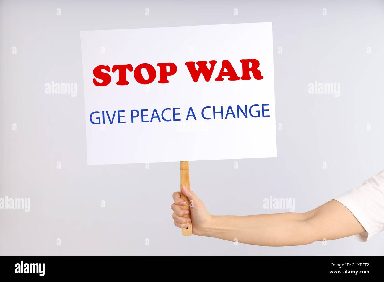 Weibliche Hand hält Protestschild mit Text: Krieg stoppen, Frieden eine Chance geben Stockfoto