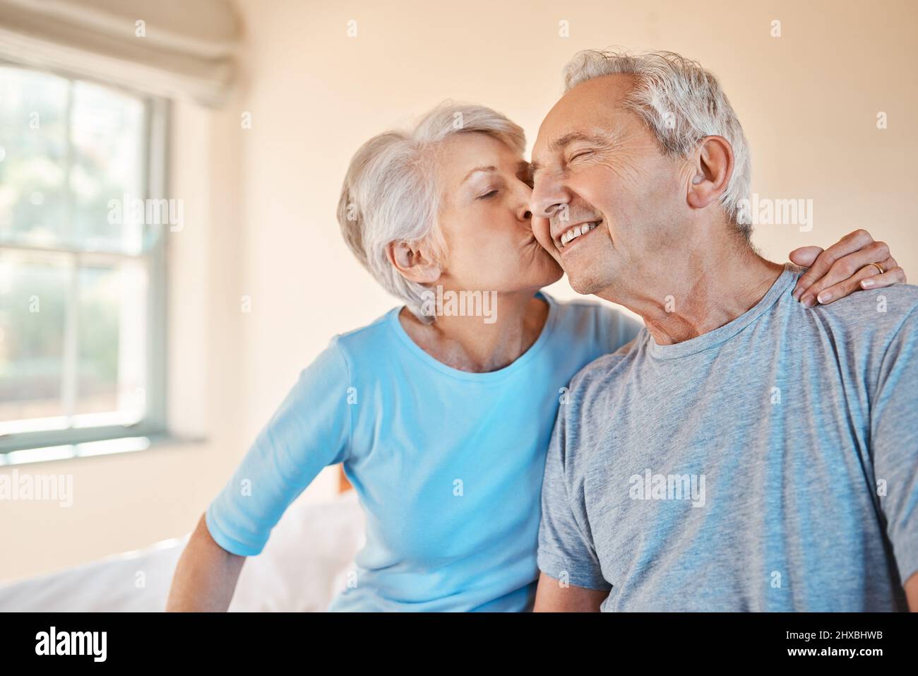 Du bist der Beste. Ausgeschnittene Aufnahme einer anhänglichen älteren Frau, die ihren glücklichen Mann in einem Pflegeheim auf die Wange küsst. Stockfoto