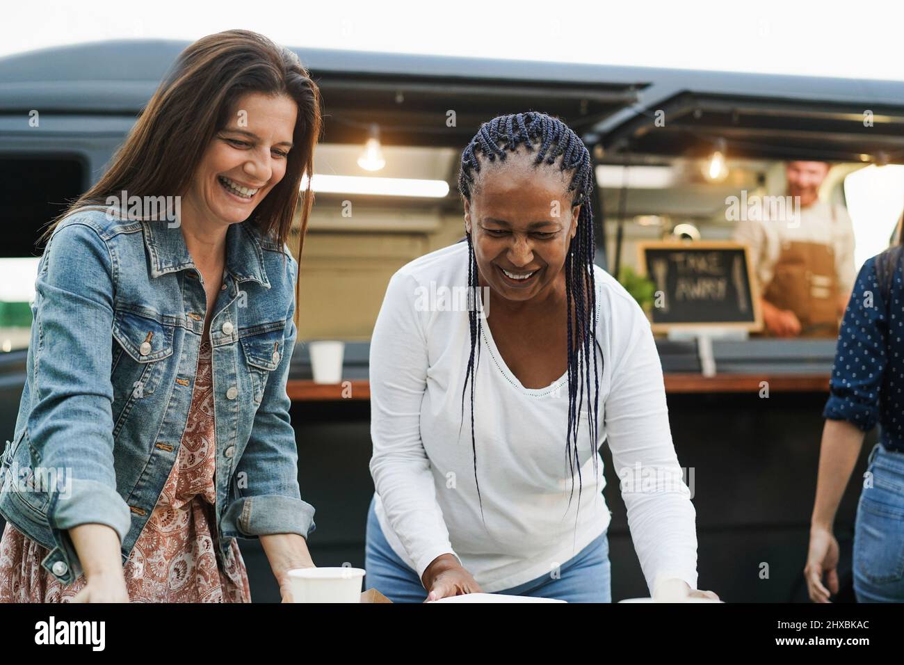 Multirassische Frauen essen im Food Truck Restaurant im Freien - Fokus auf afrikanisches weibliches Gesicht Stockfoto
