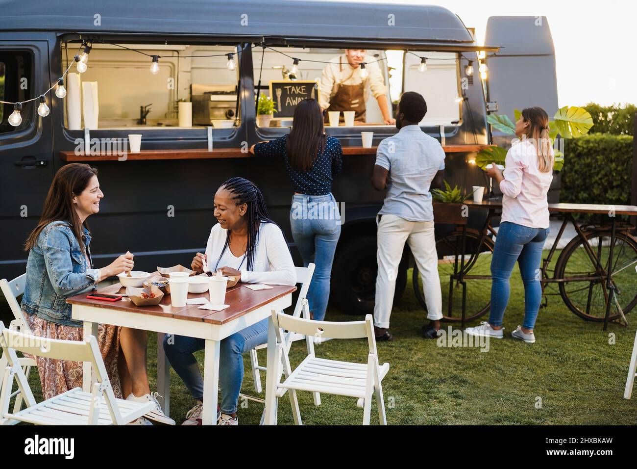Multirassische Menschen haben Spaß beim Essen im Food Truck Restaurant im Freien - Fokus auf ältere afrikanische Frau Gesicht Stockfoto