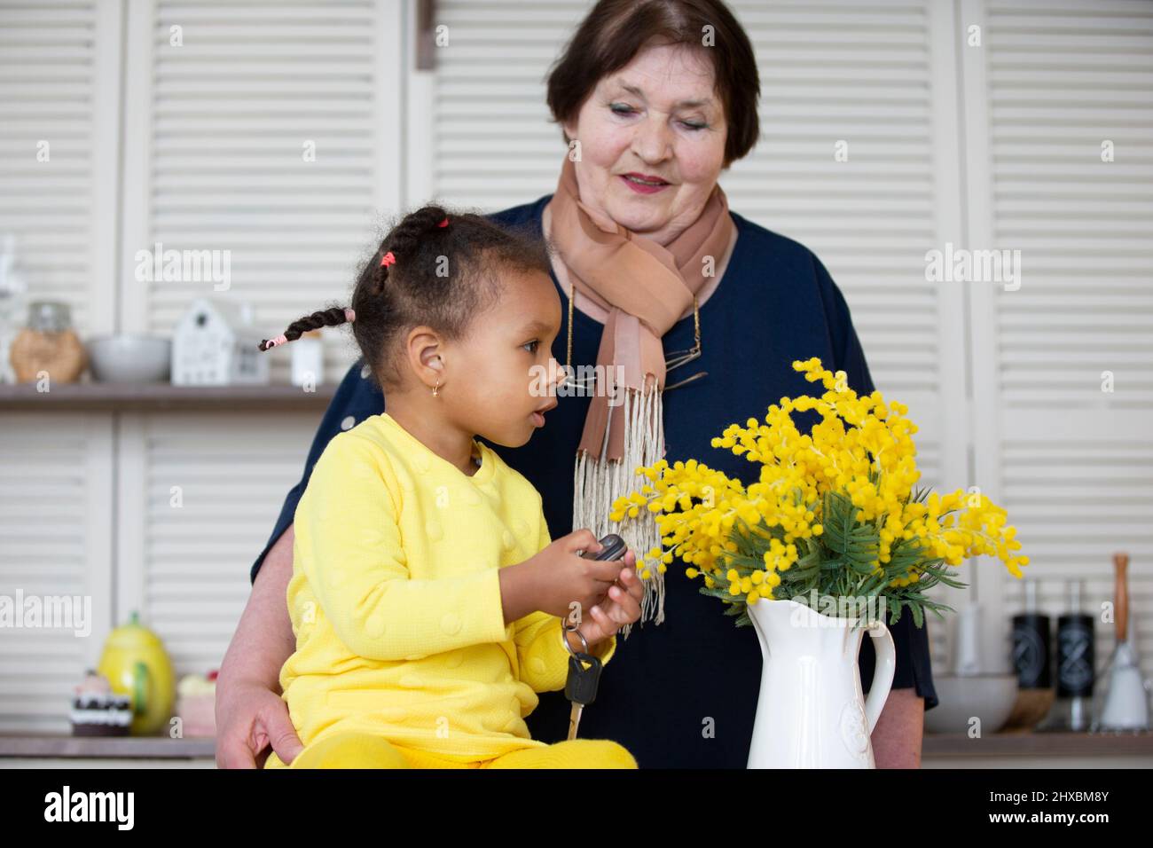 Großmutter und Enkelin aus verschiedenen Rassen. Die hellhäutige Großmutter spielt mit der dunkelhäutigen Enkelin. Stockfoto