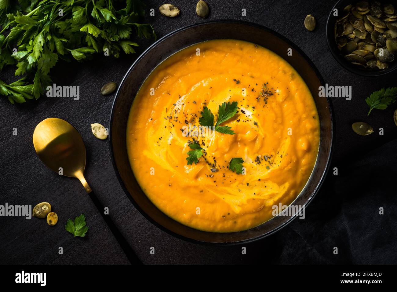 Kürbissuppenpüree mit Creme am schwarzen Tisch. Stockfoto