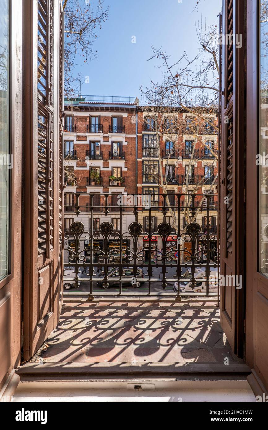 Blick auf die Stadt durch einen Balkon eines alten Gebäudes mit Blick auf die Straße mit Fenstern und hölzernen Fensterläden Stockfoto