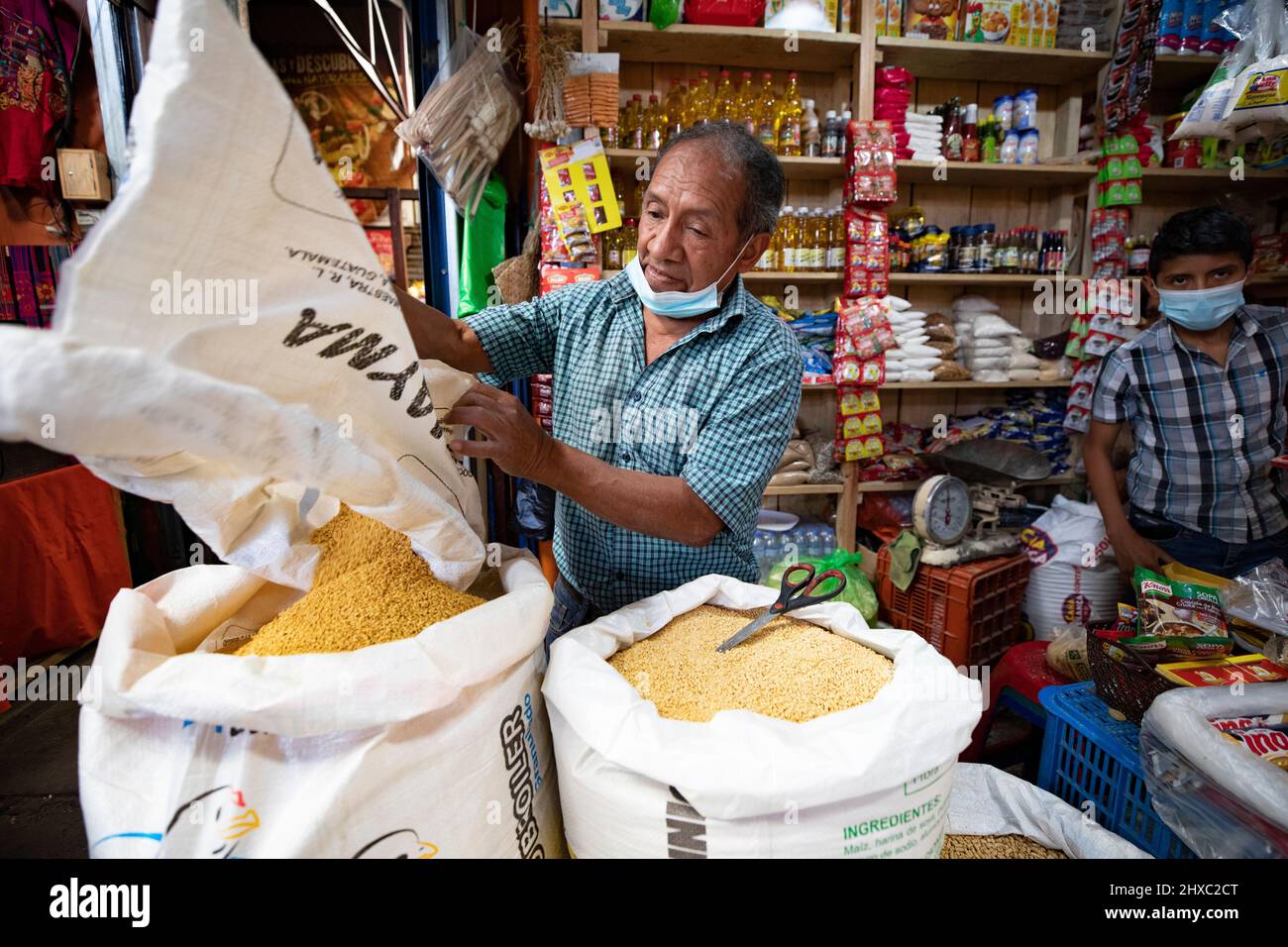Marktverkäufer, der Getreide auf dem bunten Wochenmarkt Chichicastenango Mayan Market in Guatemala, Mittelamerika, gießt. Stockfoto