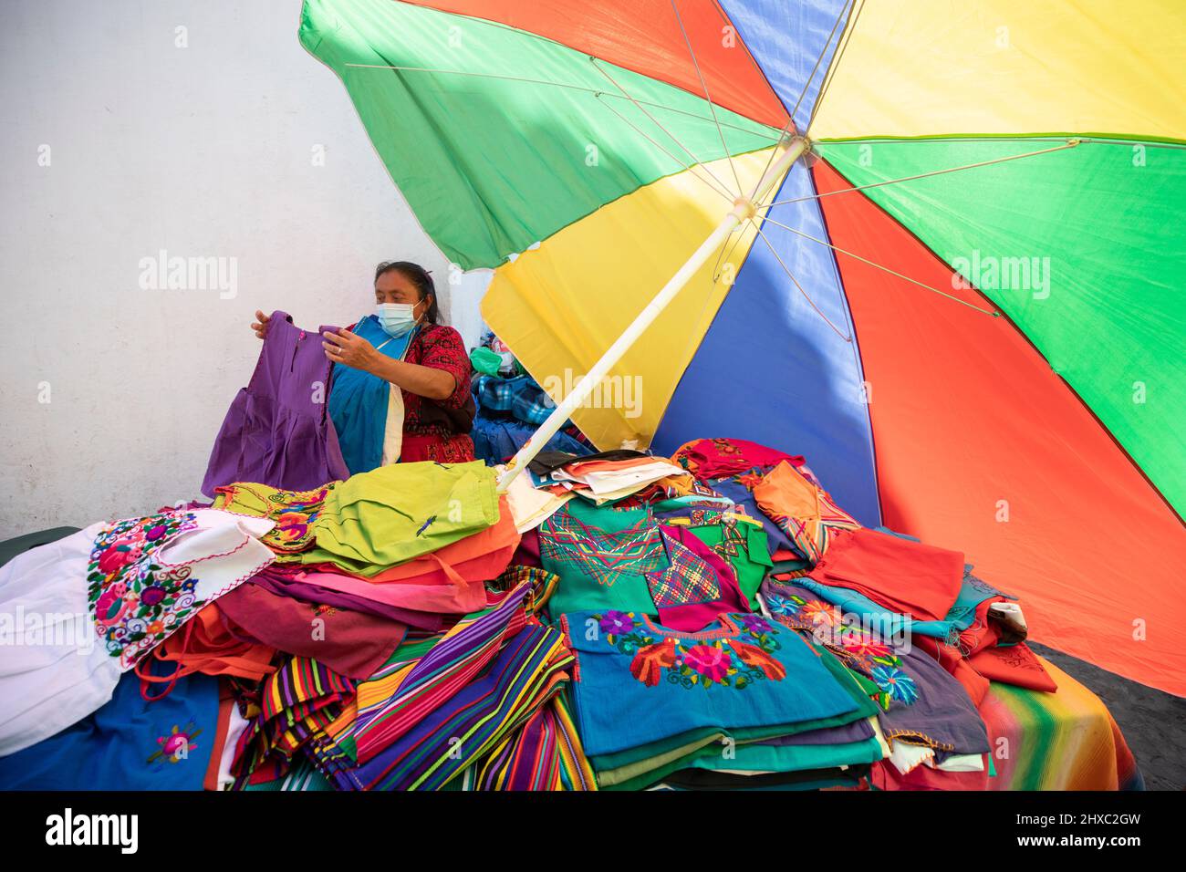 Frau, die Kleidung auf dem farbenfrohen wöchentlichen Chichicastenango Mayan Market in Guatemala, Mittelamerika, verkauft. Stockfoto