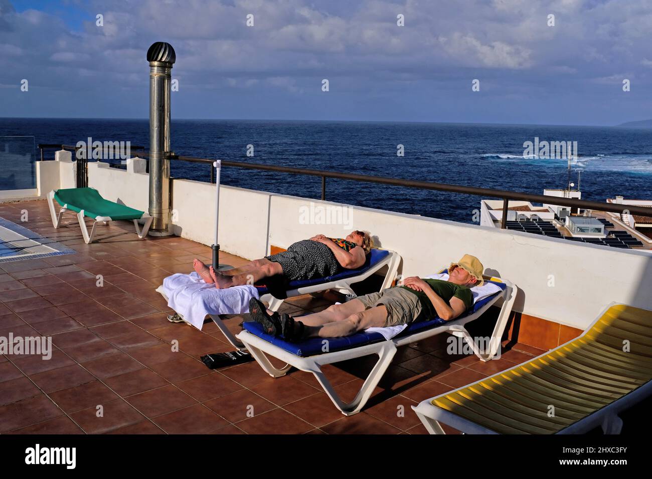 An Rentner, die auf Sonnenliegen auf einem Hoteldach auf Teneriffa schlafen. Stockfoto