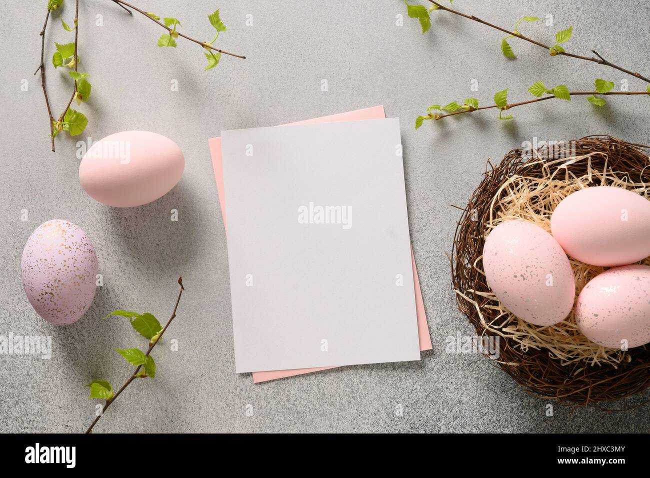 Ostern Grußkarte mit rosa Eiern im dekorativen Nest auf grauem Hintergrund. Blick von oben. Grußkarte mit Kopierplatz. Stockfoto