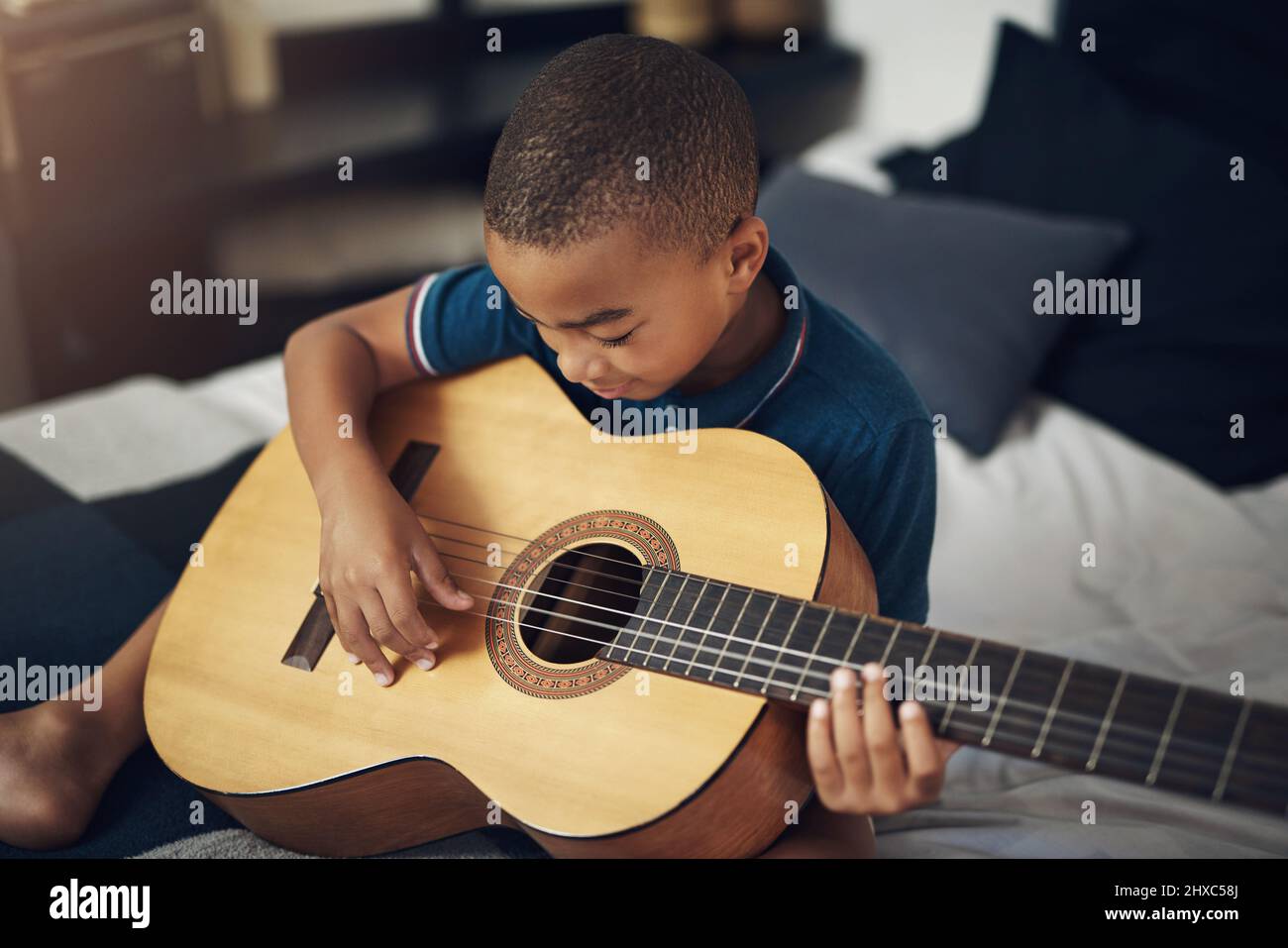 Musik stimuliert alle wichtigen Funktionen unseres Gehirns. Aufnahme eines Jungen, der zu Hause Gitarre spielt. Stockfoto