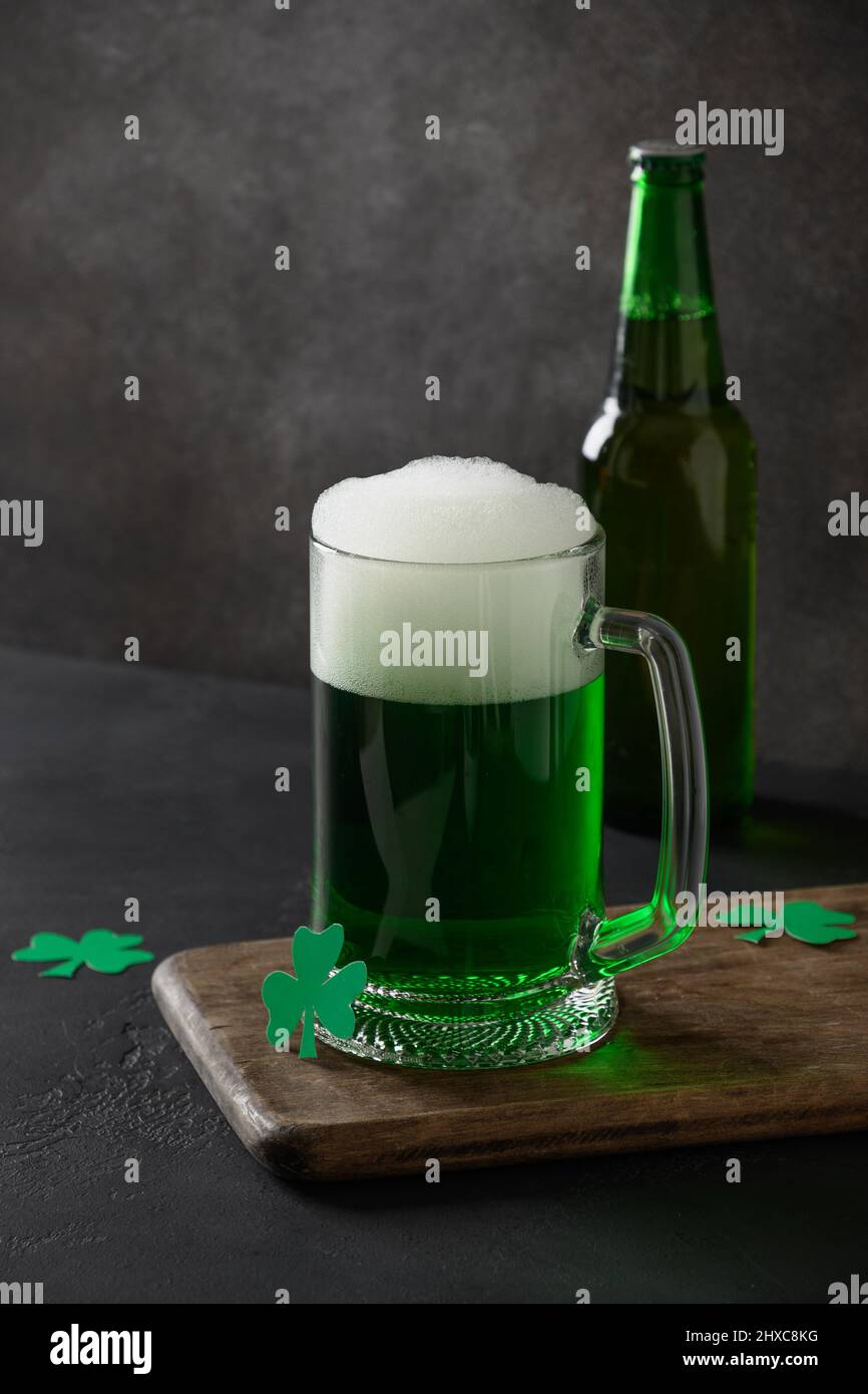 Patrick's Day traditionelles grünes Bier und Flasche auf schwarzem Hintergrund. Vertikales Format. Stockfoto
