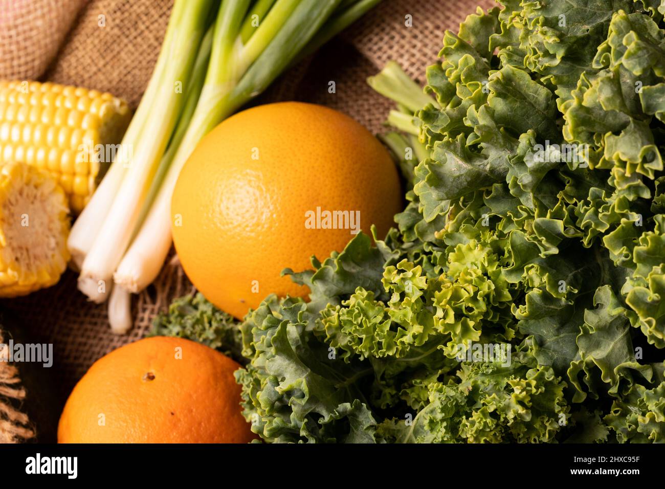 Nahaufnahme von Grünkohl, Orangen mit Frühlingszwiebel und Mais Stockfoto