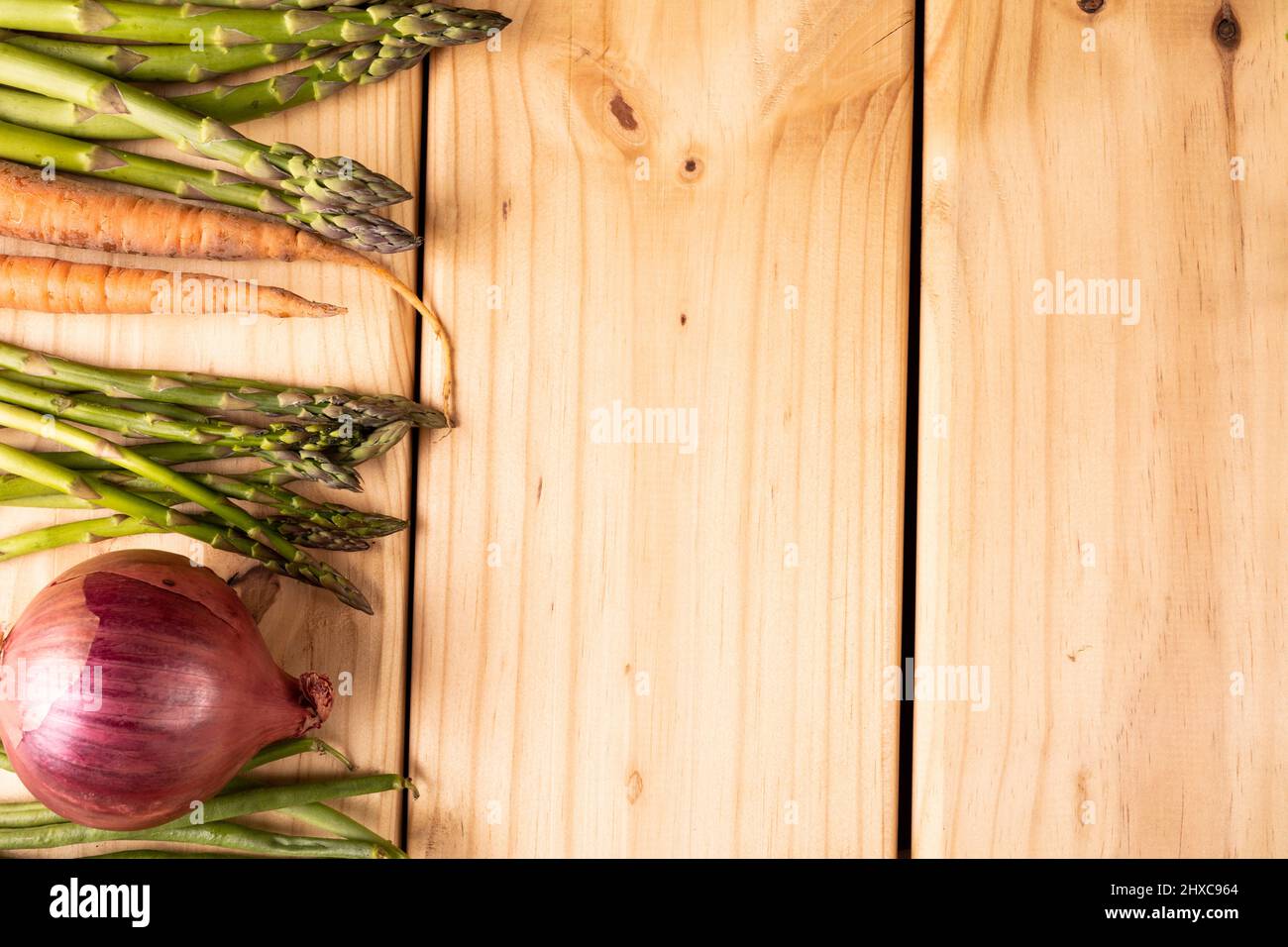 Blick von oben auf Spargel mit Karotten und Zwiebeln auf Holztisch mit leerem Raum Stockfoto