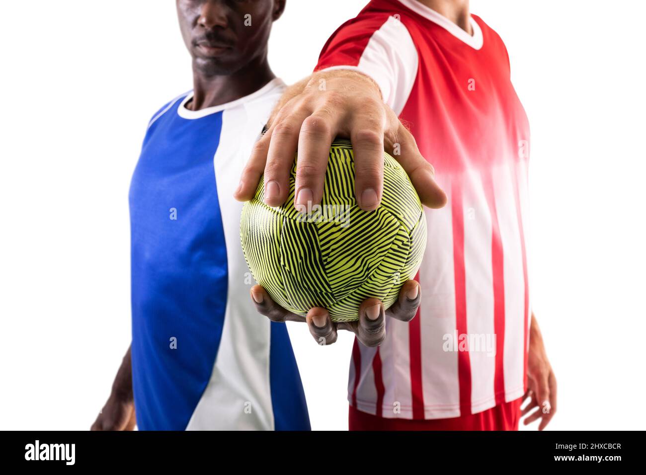 Männliche multirassische Handballspieler mit grüner Kugel, die vor weißem Hintergrund steht Stockfoto