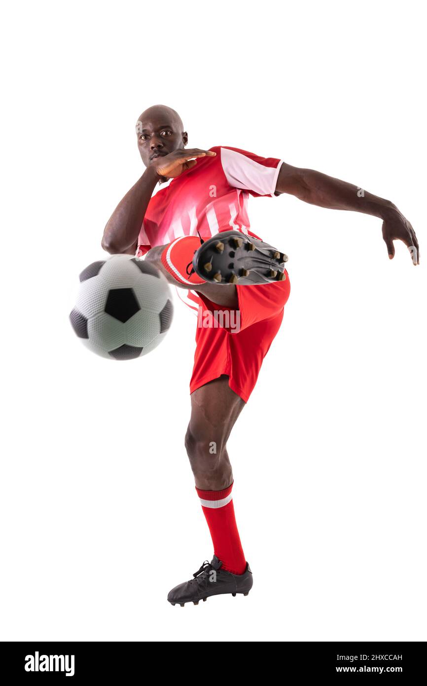 Selbstbewusster afroamerikanischer Athlet, der den Fußball auf weißem Hintergrund tritt Stockfoto