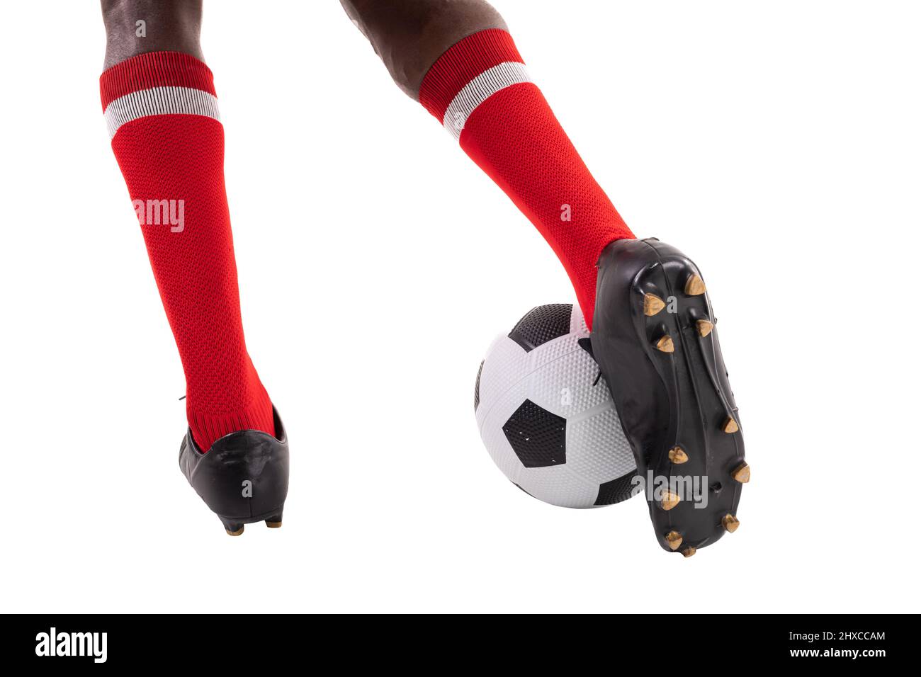 Niedriger Abschnitt des jungen afrikanischen amerikanischen Fußballspielers, der den Ball auf weißem Hintergrund tritt Stockfoto