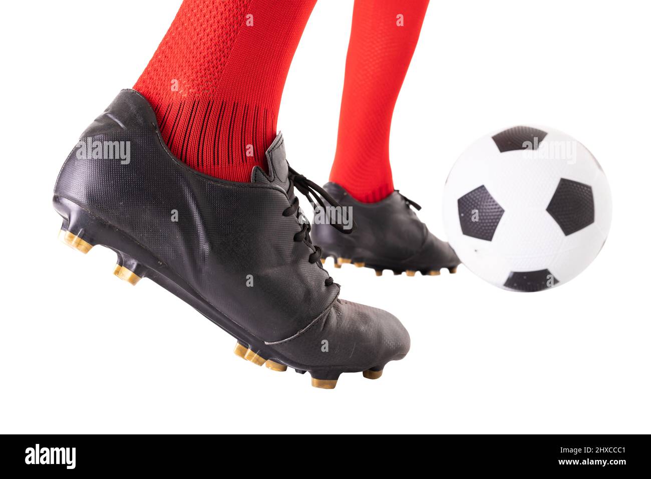 Niedriger Abschnitt eines kaukasischen Sportlers, der den Fußball auf weißem Hintergrund tritt Stockfoto