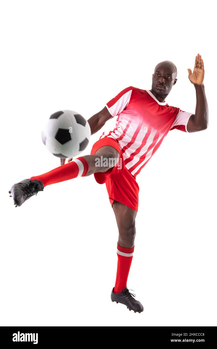 Selbstbewusster junger afroamerikanischer Fußballsportler, der den Ball vor weißem Hintergrund kicken kann Stockfoto