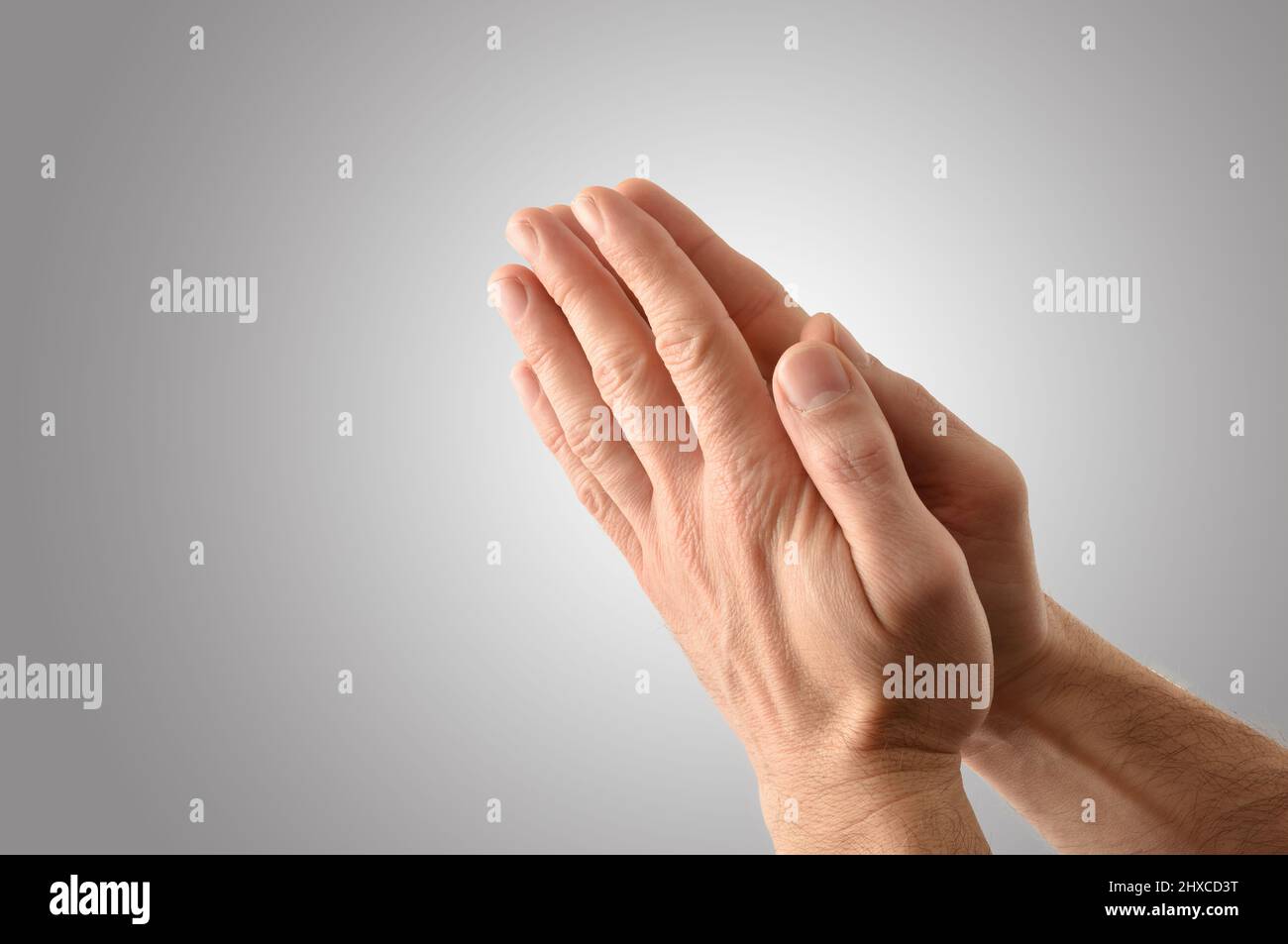 Hände eines Mannes mit Handflächen zusammen Konzept der Gebetsaktion mit isolierten grauen Hintergrund. Erhöhte Ansicht. Stockfoto