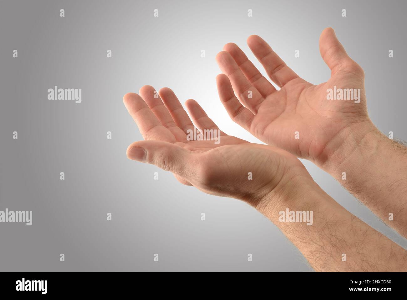 Hände mit Handflächen nach oben eines religiösen Mannes mit fragenden Gesten auf isoliertem grauem Hintergrund. Erhöhte Ansicht. Stockfoto