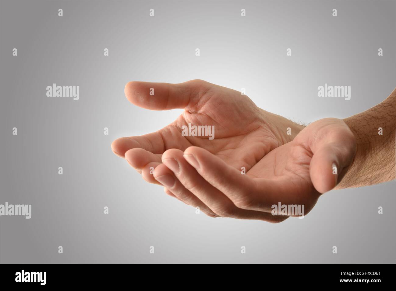 Hände mit Handflächen nach oben eines religiösen Mannes mit einer Geste des Opferens oder des Bittens mit isoliertem grauem Hintergrund. Horizontale Zusammensetzung. Stockfoto